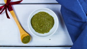 Image d'un bol avec des herbes aromatiques et une cuillère en bois sur une table blanche