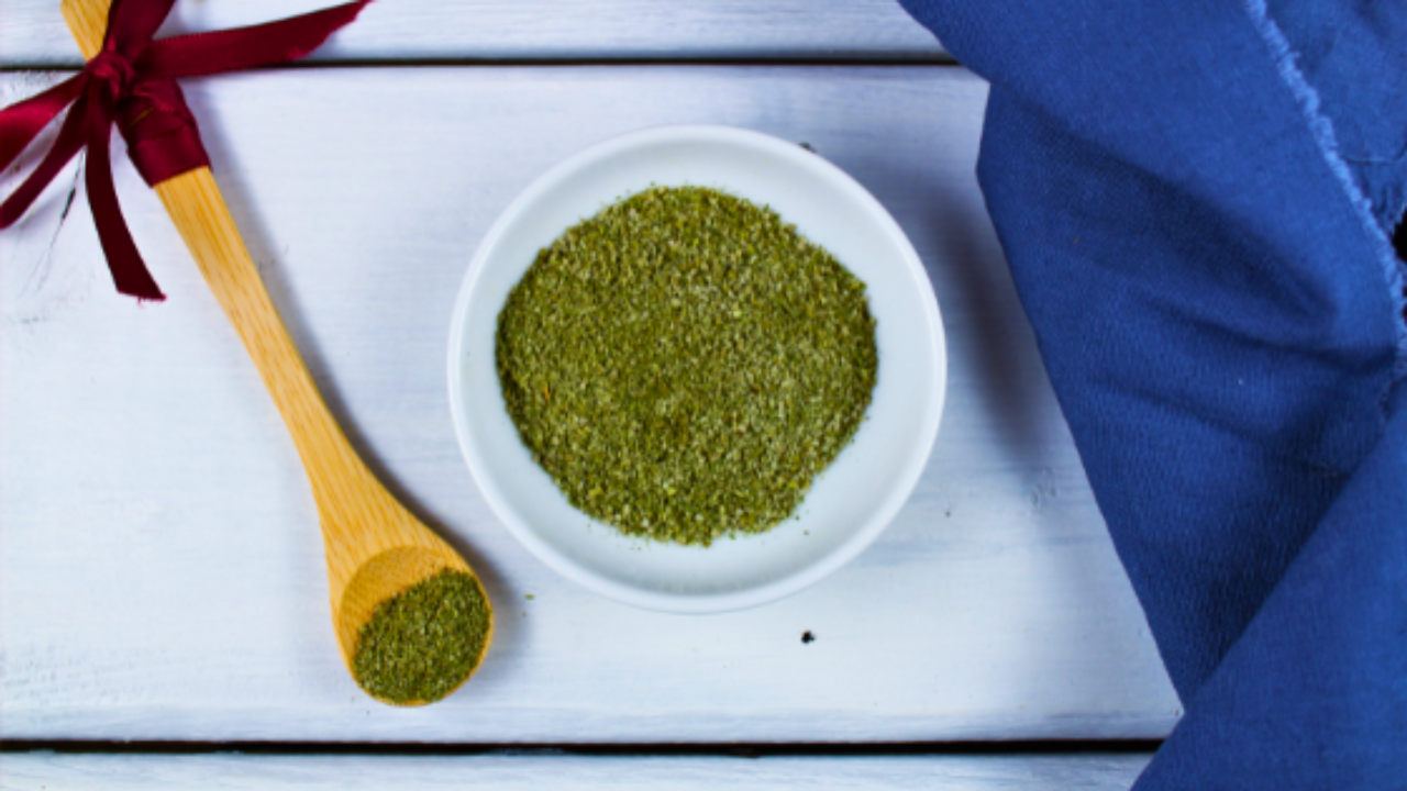 Image d'un bol avec des herbes aromatiques et une cuillère en bois sur une table blanche