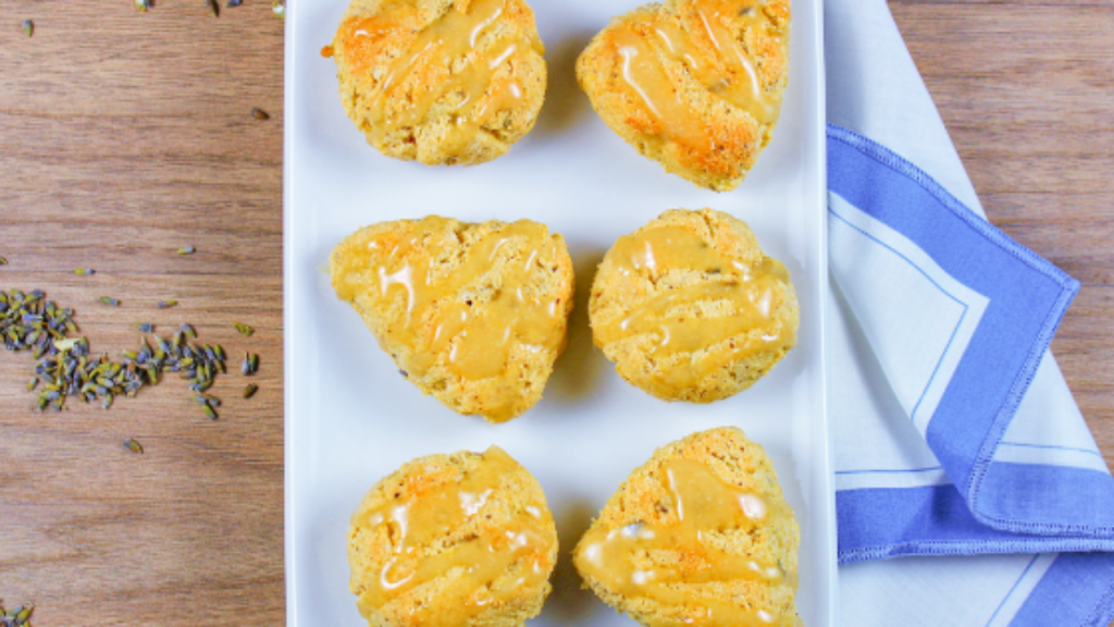 Photo des scones citron-lavande dans un plat blanc posé sur une table et des boutons de fleurs de lavande en décoration
