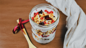 Photo de la verrine de yogourt de coco aux granolas et petits fruits dans un pot Mason vue du dessus sur une table en bois