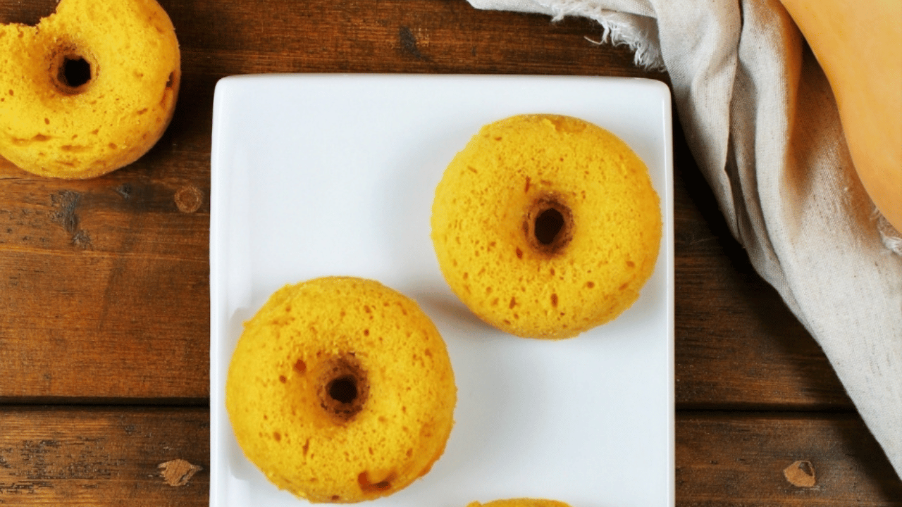 Beignes à la purée de courge & au sirop d’érable dans une assiette blanche sur une table en bois