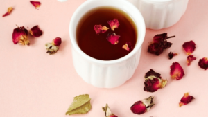 Tasse de boisson chaude sur fond rose avec des pétales rouges séchées en décoration