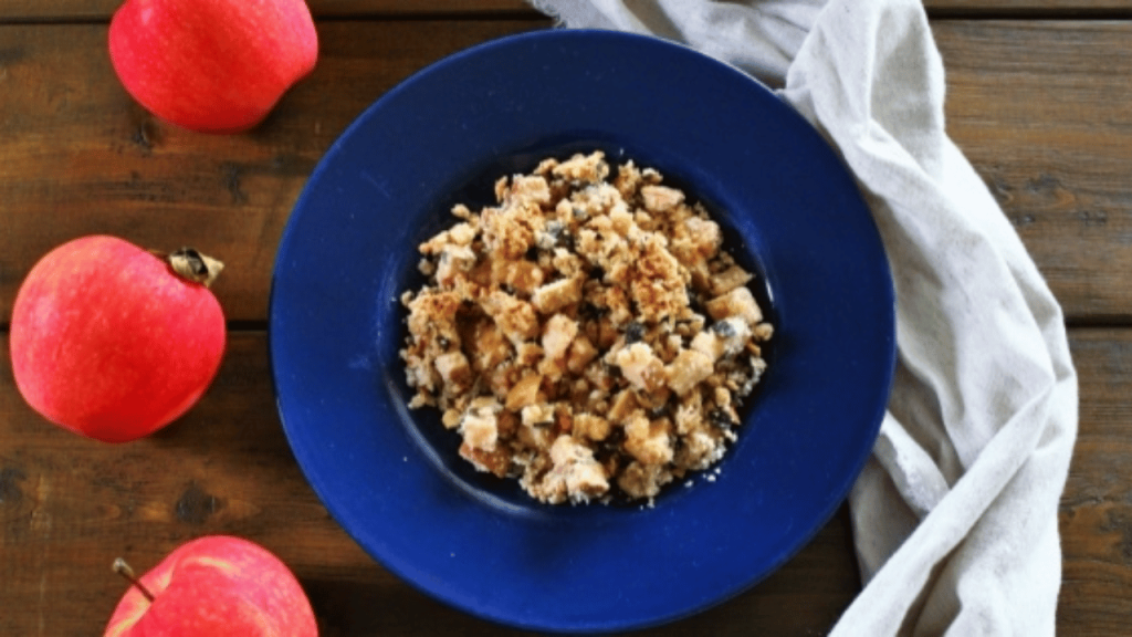 Croustade automnale aux pommes et huiles essentielles dans un bol bleu sur une table en bois et des pommes rouges fraîches entières en décoration